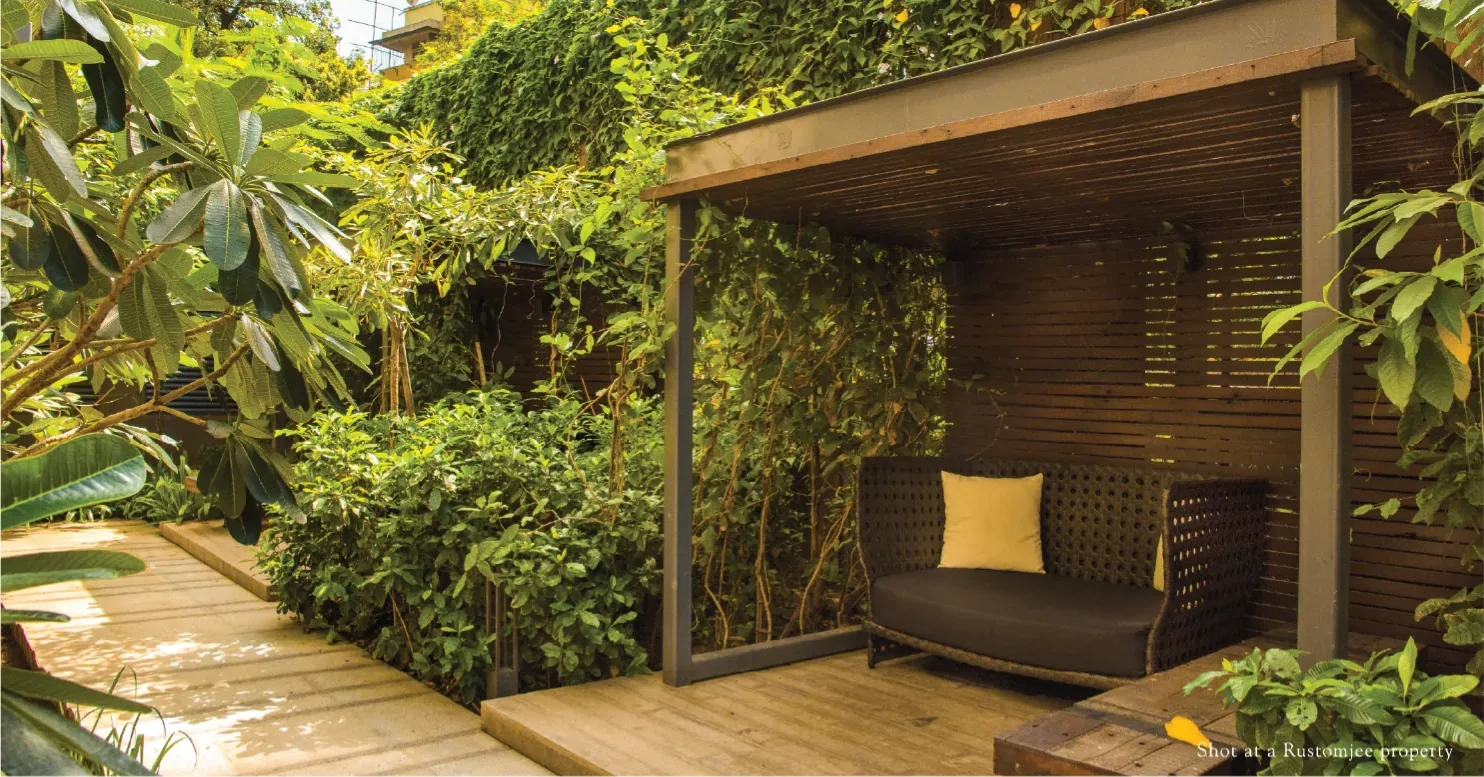 Shaded timber deck and garden seating in a landscaped courtyard at a Rustomjee property, representative of the landscaping at Rustomjee Urban Woods