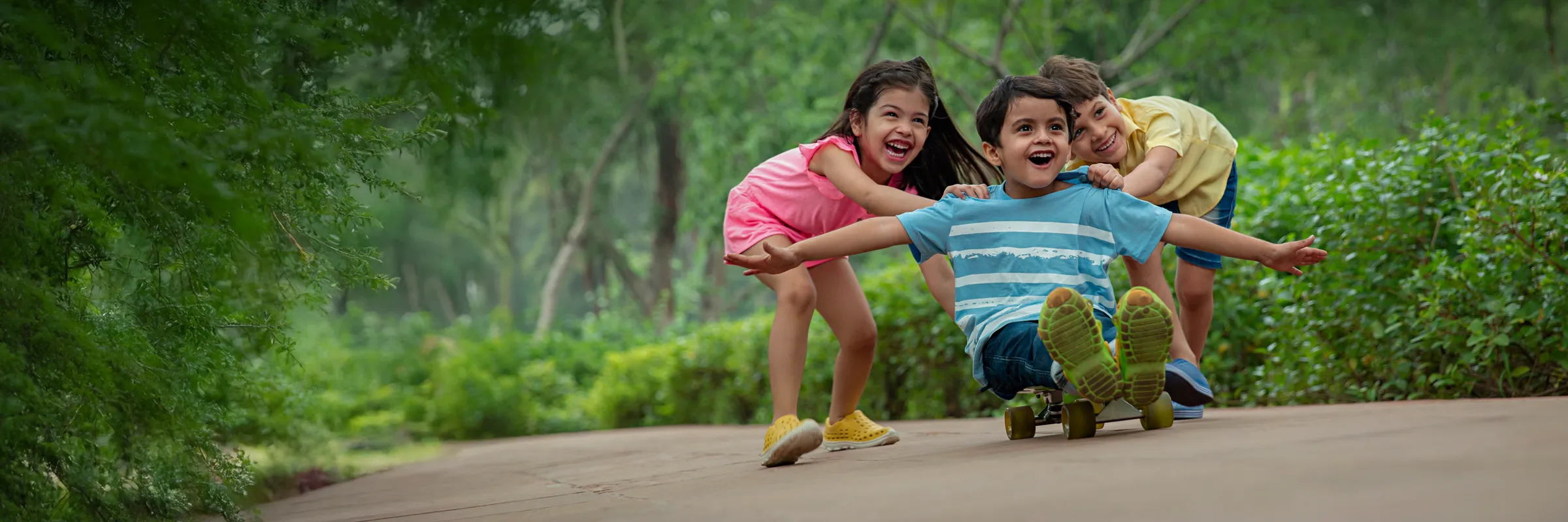 Children playing on a shaded garden path at Rustomjee Urban Woods, Dombivli East