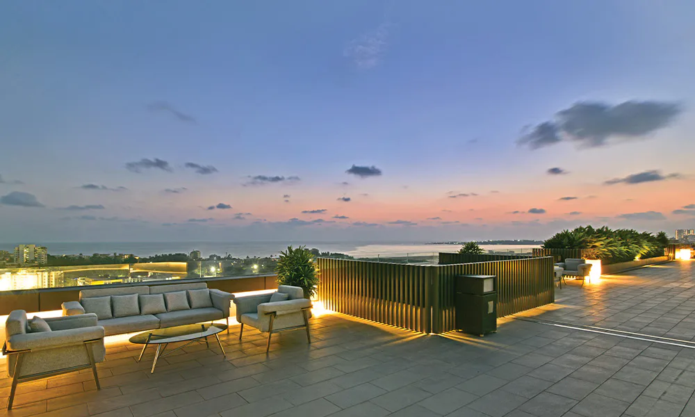 Rooftop sundeck with lounge seating at dusk at Rustomjee Urban Woods