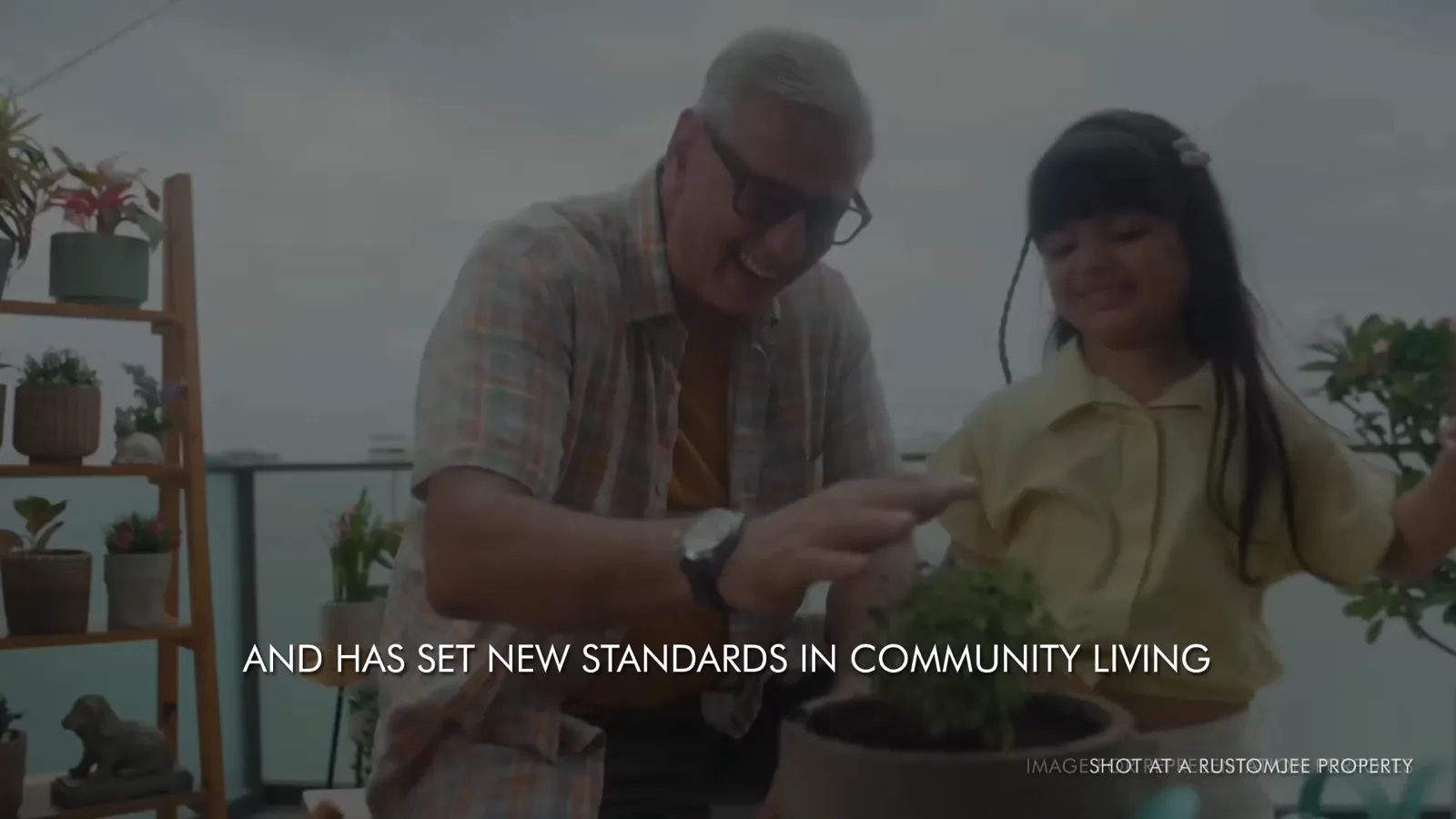 Still frame from the Rustomjee Urban Woods walkthrough film: a grandfather and a child planting on a terrace garden